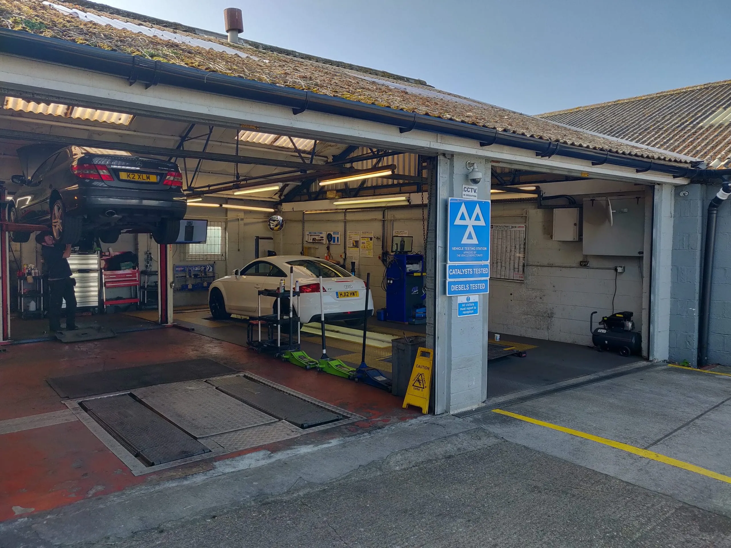 The Carwise workshop from the yard, a car up on the lift and the MOT testing station sign